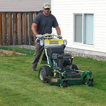 A man is pushing a lawn mower in the yard.