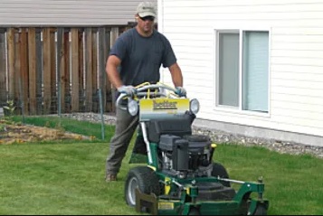 A man is pushing a lawn mower in the yard.