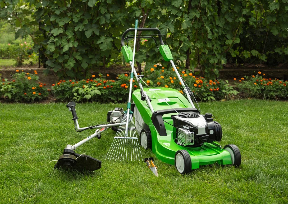 A green lawn mower and other equipment in the grass.