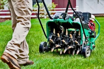 A person standing next to a green lawn mower.